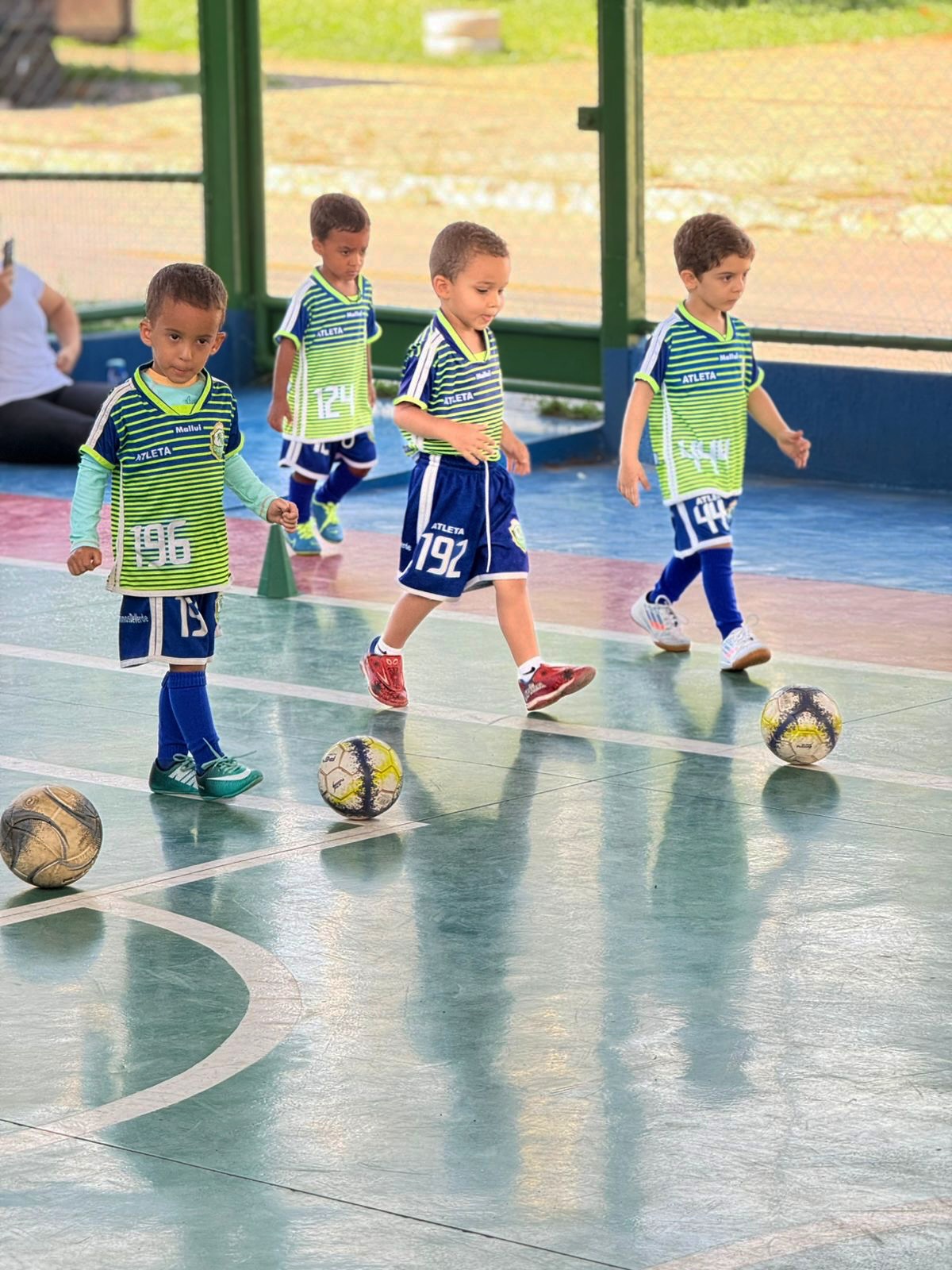 Alunos conduzindo a bola em fila durante o treino